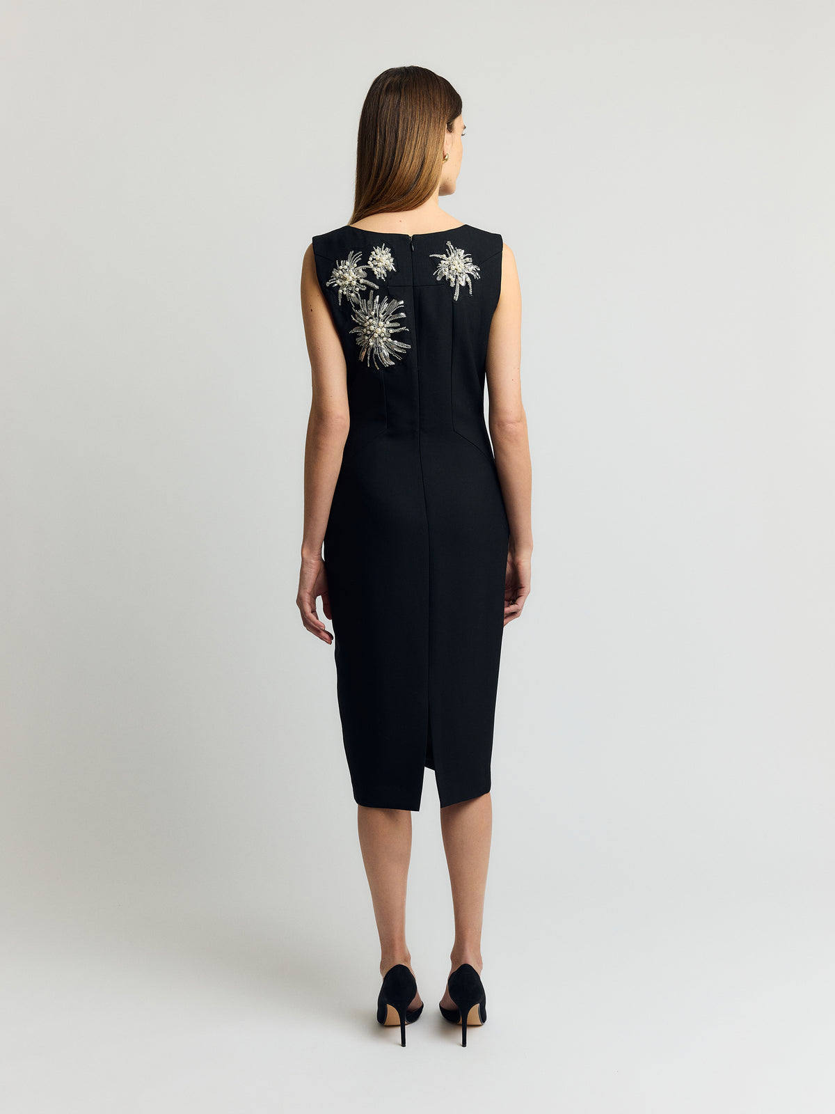 Musta hihaton cocktailmekko takaa, pyöreä pääntie, leveät olkaimet ja helmin koristellut paljettikukat yläosassa